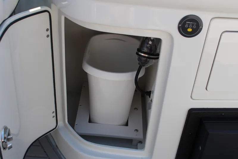 Slide: The Image of 2023 Crownline E285 boat storage compartment with a white trash bin inside. - 40