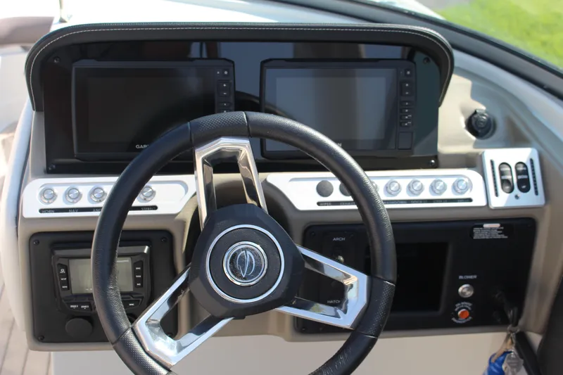 Slide: The Image of 2023 Crownline E285 boat dashboard with steering wheel and dual display screens. - 44