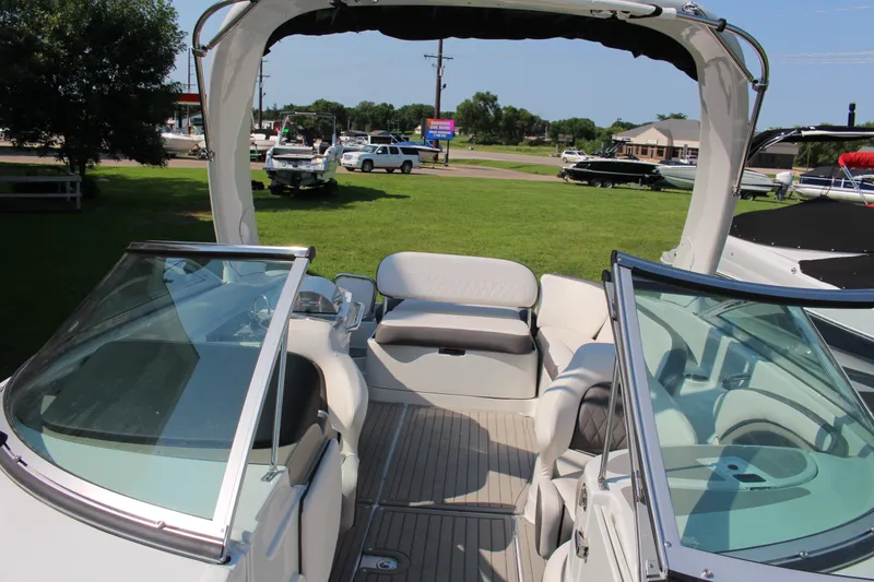 Slide: The Image of 2023 Crownline E285 boat interior with seating, windshield, and open deck in a grassy area. - 56