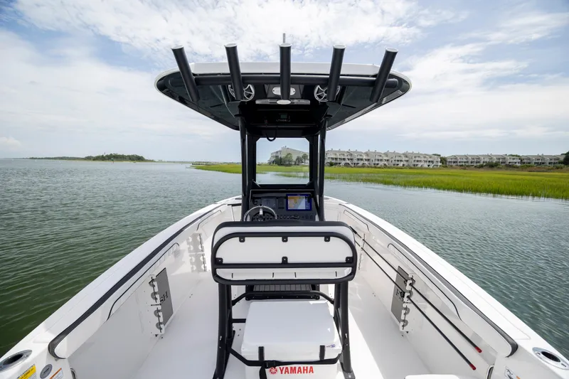 Slide: The Image of 2024 Yamaha Boats 255 FSH Sport H on serene waterway, showcasing helm and seating. - 10
