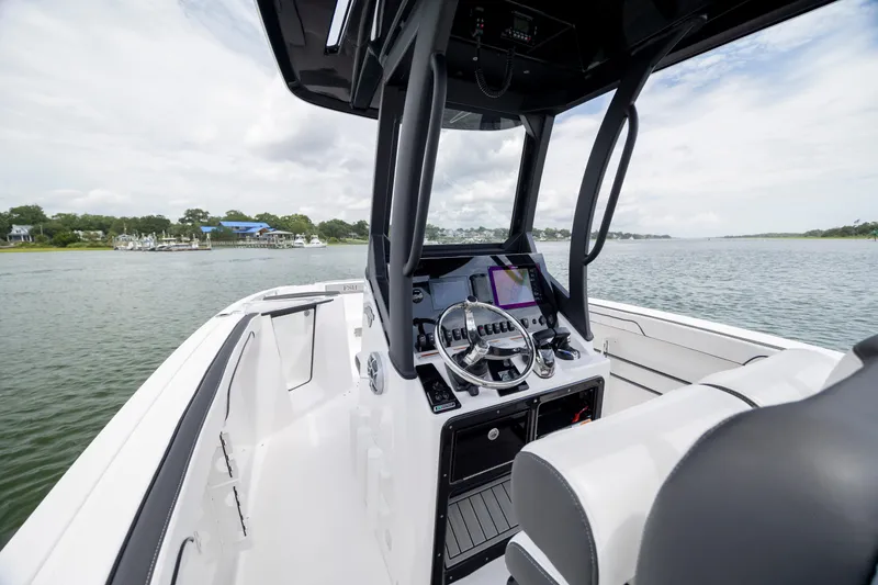 Slide: The Image of 2024 Yamaha Boats 255 FSH Sport H interior with steering console on calm water. - 12