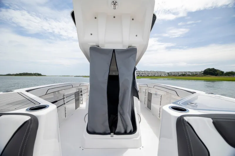 Slide: The Image of 2024 Yamaha Boats 255 FSH Sport H interior, featuring sleek seating and storage, on a calm waterway. - 21