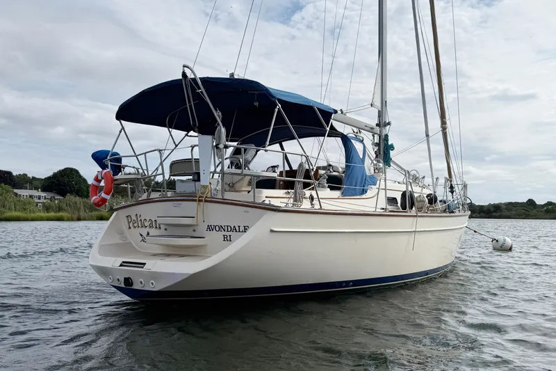 Slide: The Image of 2008 Island Packet 370 sailboat anchored on calm water with blue canopy. - 3