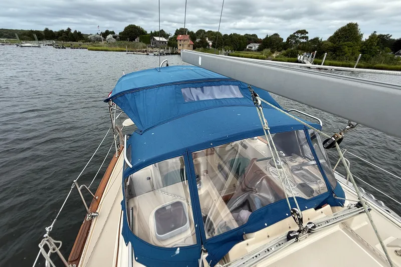 Slide: The Image of 2008 Island Packet 370 sailboat with blue canopy, docked in a serene harbor. - 35
