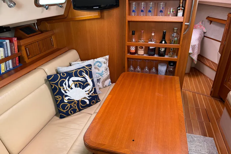 Slide: The Image of Cozy 2008 Island Packet 370 yacht interior with wooden table, cushions, and bar area. - 41