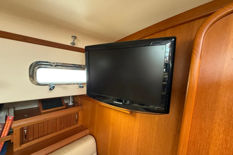 Slide: The Image of Flat-screen TV in 2008 Island Packet 370 yacht interior, wooden paneling, and porthole window. - 43
