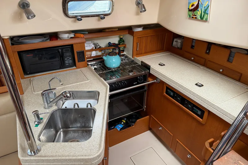 Slide: The Image of Compact kitchen in a 2008 Island Packet 370 sailboat with sink, stove, and microwave. - 49