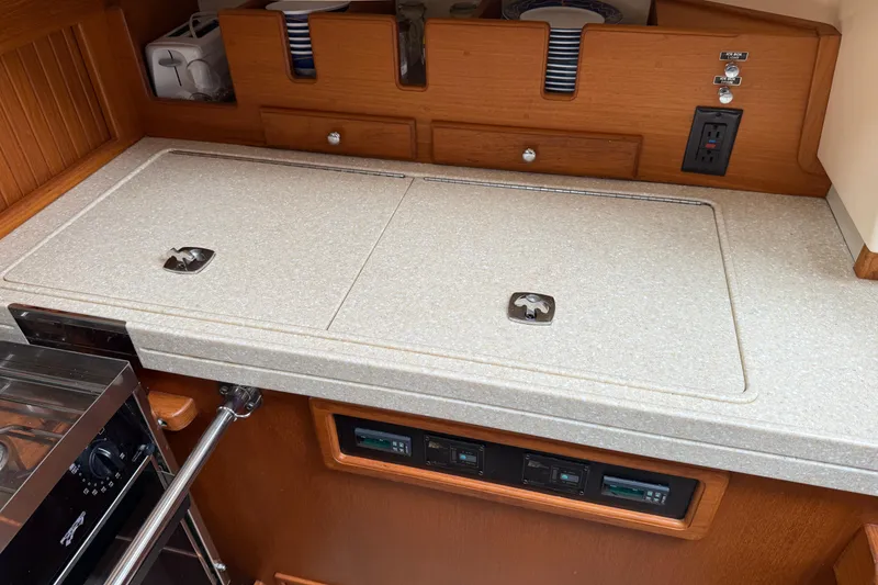 Slide: The Image of 2008 Island Packet 370 yacht galley with countertop, stove, and storage compartments. - 55