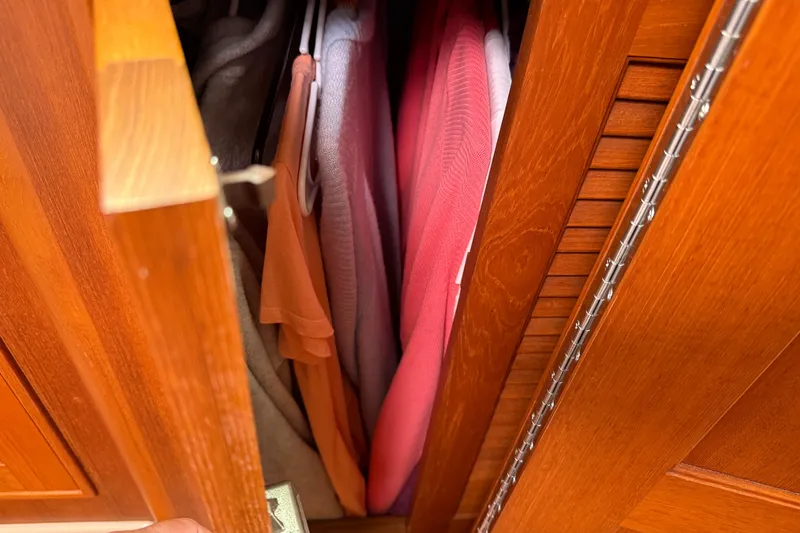 Slide: The Image of Wooden closet with colorful clothes inside, aboard a 2008 Island Packet 370 sailboat. - 65