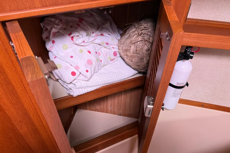Slide: The Image of Open wooden cabinet on 2008 Island Packet 370 yacht with linens and fire extinguisher. - 66