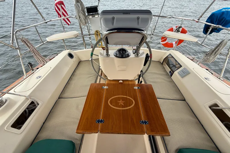 Slide: The Image of 2008 Island Packet 370 sailboat cockpit with wooden table, steering wheel, and nautical equipment. - 7