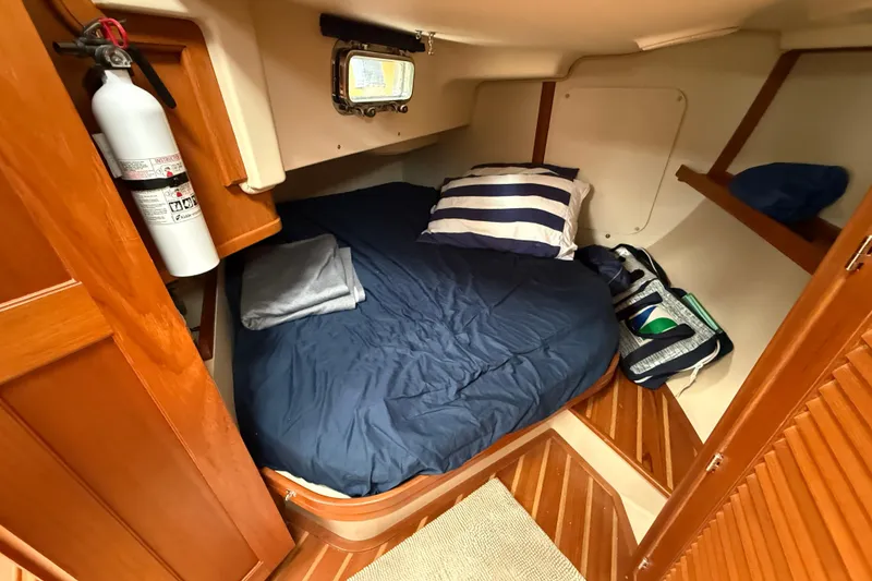 Slide: The Image of Cozy cabin interior of 2008 Island Packet 370 sailboat with bed and fire extinguisher. - 71
