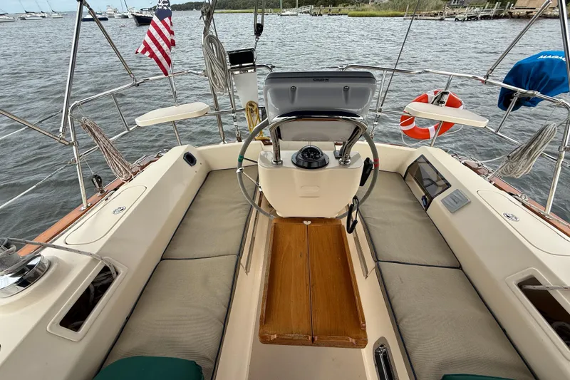 Slide: The Image of Cockpit of 2008 Island Packet 370 sailboat with steering wheel and seating, docked by the water. - 8