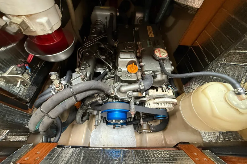 Slide: The Image of Engine compartment of a 2008 Island Packet 370 sailboat, showcasing mechanical components and hoses. - 80
