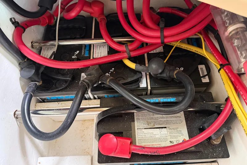 Slide: The Image of Battery compartment with red and black cables in a 2008 Island Packet 370 sailboat. - 83