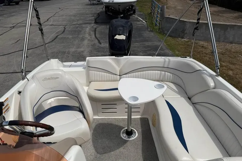 Slide: The Image of 2006 Hurricane GS194 Fundeck boat interior with seating and table, parked on pavement. - 12