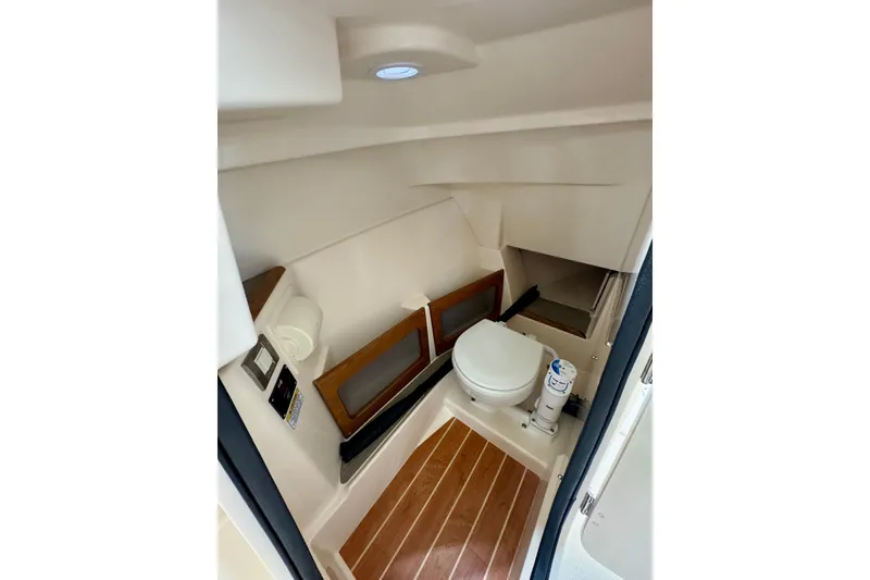 Slide: The Image of 2026 Grady-White Freedom 235 boat interior with compact marine toilet and wooden flooring. - 8