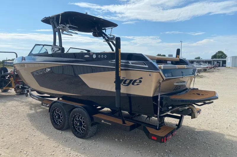 Slide: The Image of 2021 Tigé 23RZX boat on trailer, sleek design, parked outdoors under blue sky. - 3