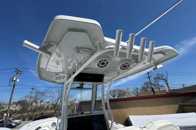 Slide: The Image of 2025 Tidewater 282 CC Adventure boat with rod holders and speakers under a clear blue sky. - 11