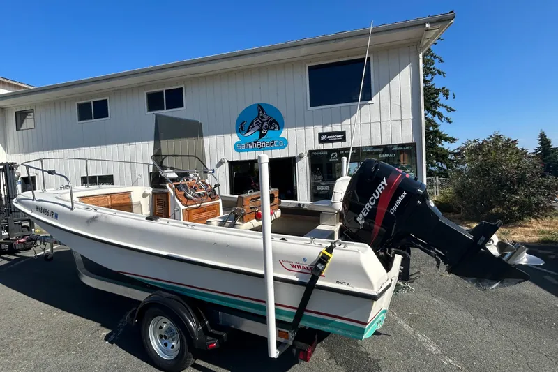Slide: The Image of 1977 Boston Whaler 19 Outrage boat with Mercury engine on trailer, parked outside a building. - 2