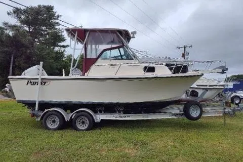 Slide: The Image of 1996 Parker 2110 Walkaround boat on trailer, parked on grass under cloudy sky. - 1