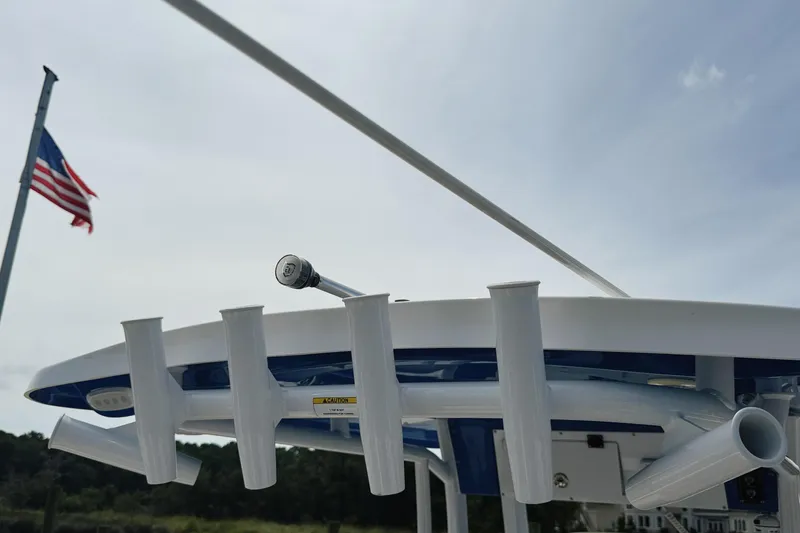 Slide: The Image of 2023 Sea Pro 239 DLX boat with rod holders, American flag in background. - 13