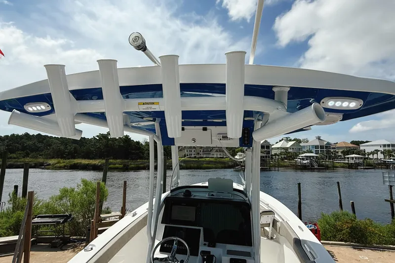 Slide: The Image of 2023 Sea Pro 239 DLX boat with rod holders and canopy, docked by a scenic waterfront. - 14
