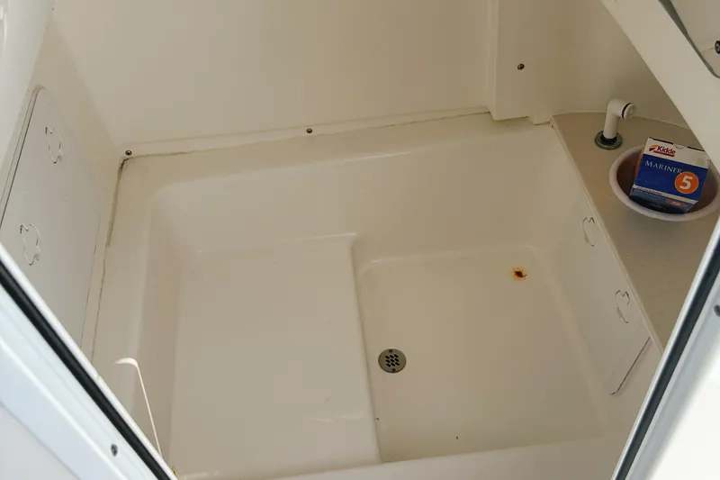 Slide: The Image of 2023 Sea Pro 239 DLX boat interior storage compartment with drain and safety equipment. - 28