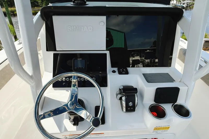 Slide: The Image of 2023 Sea Pro 239 DLX boat console with steering wheel, Simrad display, and controls. - 29