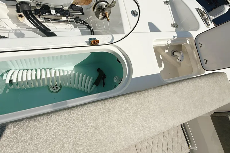 Slide: The Image of 2023 Sea Pro 239 DLX boat interior with storage compartments and coiled hose. - 30