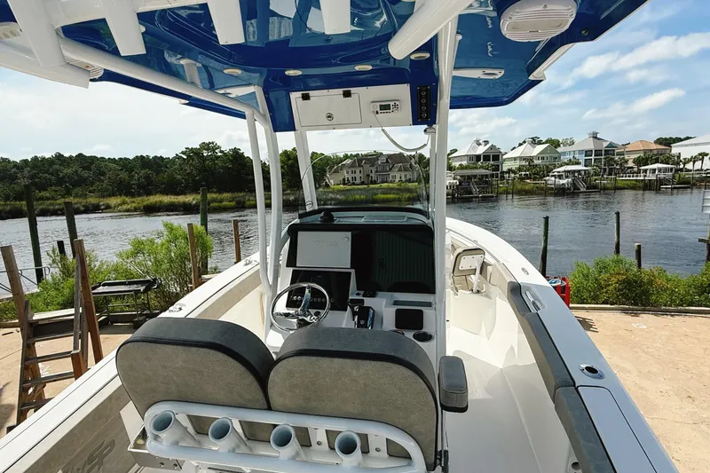 Slide: The Image of 2023 Sea Pro 239 DLX boat interior with dual seats, steering wheel, and waterfront view. - 32