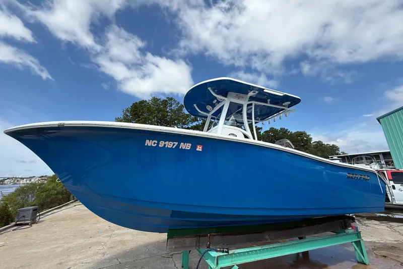Slide: The Image of 2023 Sea Pro 239 DLX boat in vibrant blue, docked under a partly cloudy sky. - 4