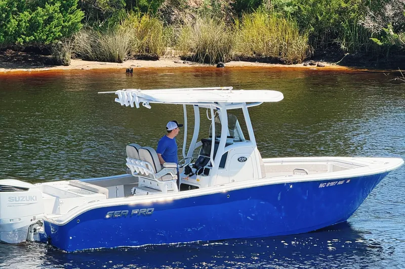 Slide: The Image of 2023 Sea Pro 239 DLX boat on water, featuring blue hull and Suzuki engine. - 6