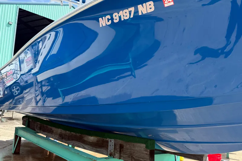 Slide: The Image of 2023 Sea Pro 239 DLX boat with blue hull, docked and reflecting surroundings. - 7