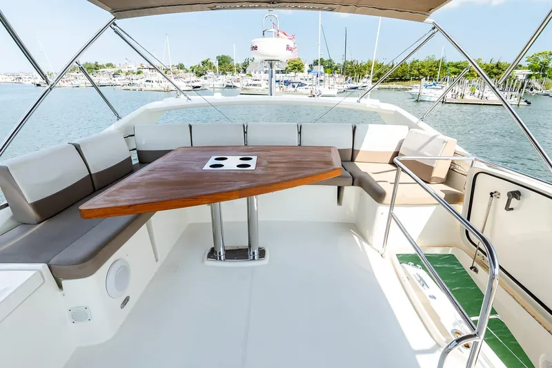 Slide: The Image of Flybridge seating area on 2014 Prestige Yachts 550, featuring a wooden table and marina view. - 11