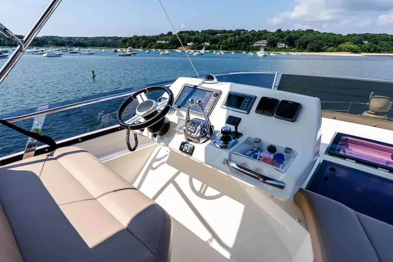 Slide: The Image of Flybridge helm of 2014 Prestige Yachts 550, overlooking serene waters and distant boats. - 26