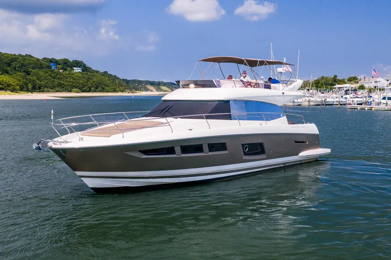 Slide: The Image of 2014 Prestige Yachts 550 Flybridge cruising near a marina under a clear blue sky. - 59