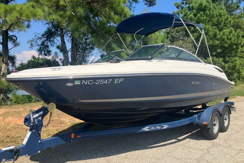 Slide: The Image of 2013 Sea Ray 210 SLX boat on trailer, parked near trees. - 10