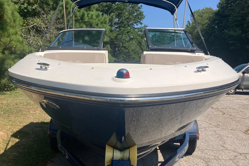Slide: The Image of 2013 Sea Ray 210 SLX boat on trailer, parked outdoors with trees in background. - 11