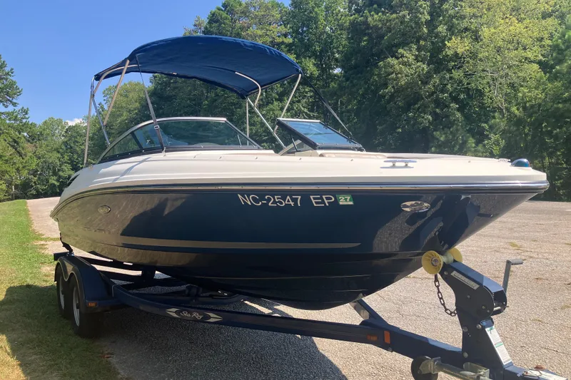 Slide: The Image of 2013 Sea Ray 210 SLX boat on trailer, parked outdoors with trees in background. - 12