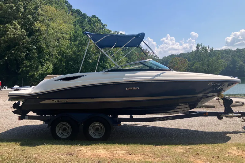 Slide: The Image of 2013 Sea Ray 210 SLX boat on trailer, parked near a scenic lake. - 13