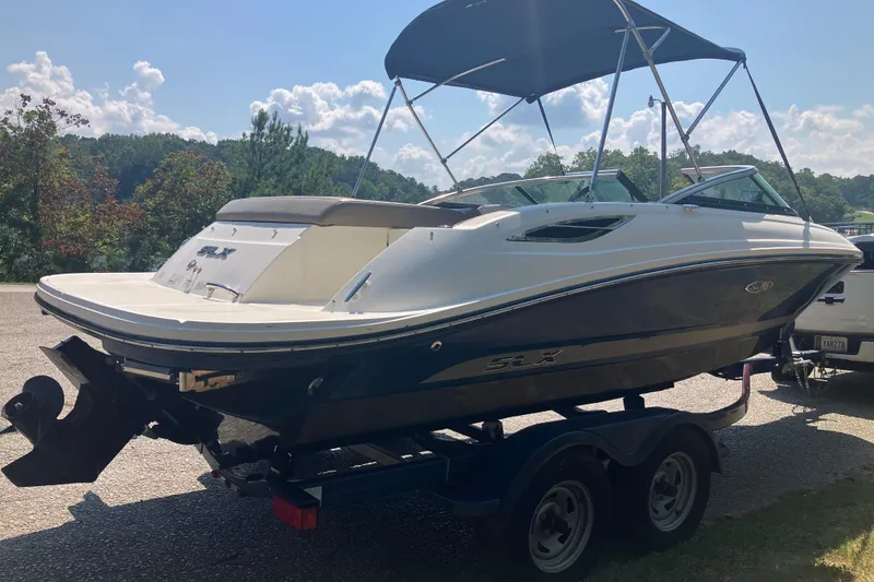 Slide: The Image of 2013 Sea Ray 210 SLX boat on trailer with canopy, parked outdoors. - 14