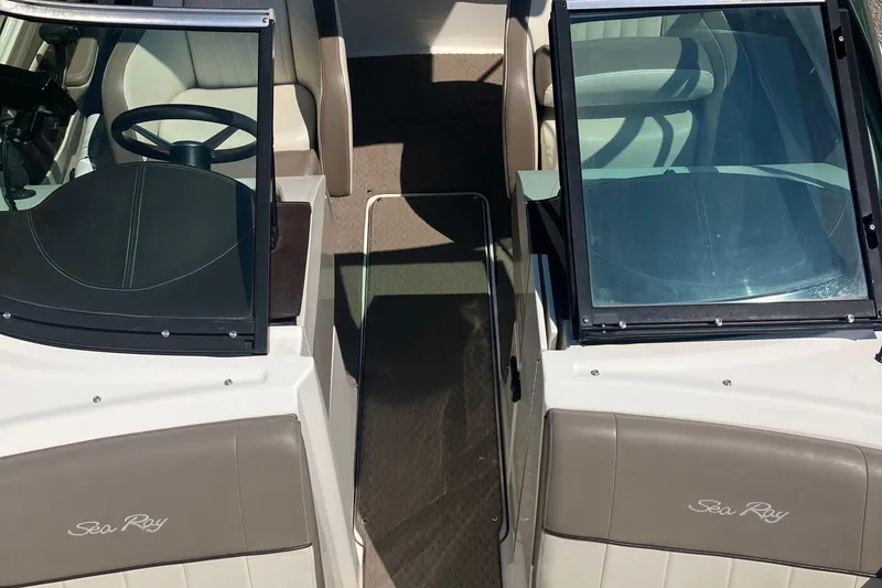 Slide: The Image of 2013 Sea Ray 210 SLX boat interior with dual windshields and beige seating. - 26