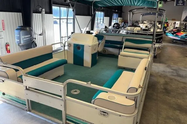 Slide: The Image of 1997 Crest Sport pontoon boat with teal and white seating in a showroom. - 5