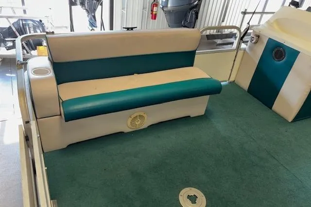 Slide: The Image of 1997 Crest Sport boat interior with teal and beige seating, green carpet, and cup holder. - 6