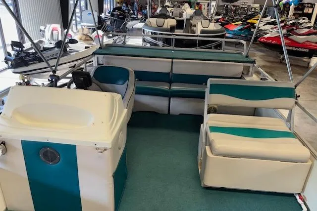 Slide: The Image of 1997 Crest Sport boat interior with teal and white seating, displayed in a showroom. - 8