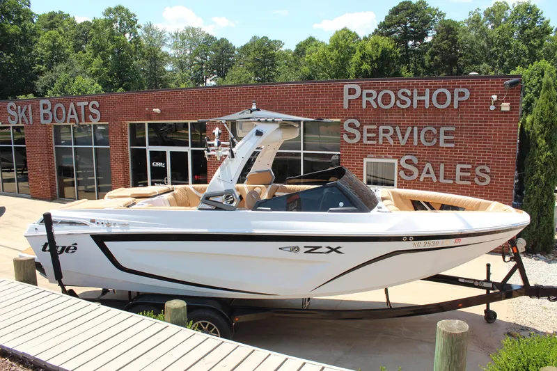 Slide: The Image of 2021 Tigé 23ZX boat displayed outside a ski boat dealership. - 6