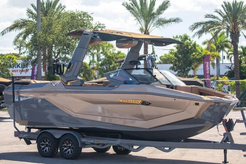 Slide: The Image of 2024 Nautique Super Air Nautique G23 Paragon boat on trailer, surrounded by palm trees. - 47