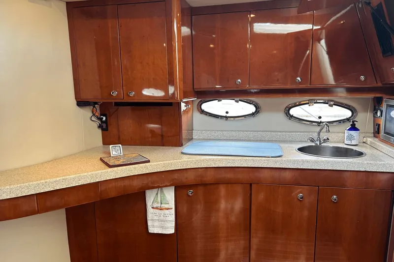 Slide: The Image of Luxurious 2005 Regal Commodore 4260 yacht kitchen with wood cabinets and oval windows. - 15