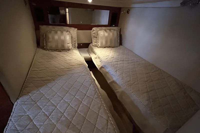 Slide: The Image of Twin beds in a 2005 Regal Commodore 4260 yacht cabin, featuring quilted bedding. - 28